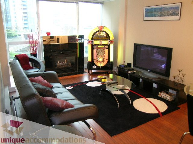 Spacious living room with a retro jukebox, hardwood floors, and a city view. - 603 - 1328 West Pender, Vancouver Downtown