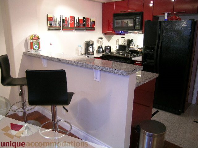 Bright kitchen with granite countertops, red cabinets, and black appliances, perfect for a cozy downtown condo.