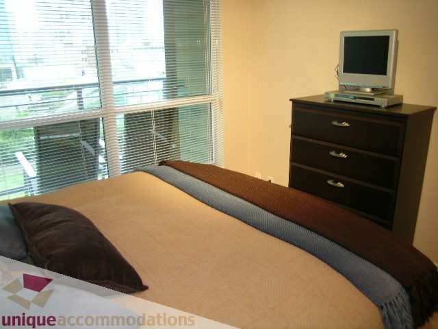 Spacious 1-bedroom + den with cozy bed, city view, and compact TV setup. - 603 - 1328 West Pender, Vancouver Downtown