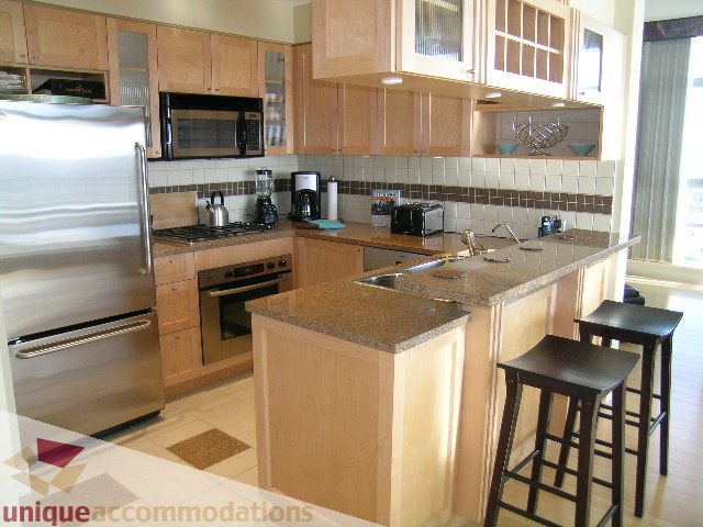 Modern kitchen with granite countertops, stainless steel appliances, and a breakfast bar. - 3005 - 1483 Homer Street, Vancouver Downtown