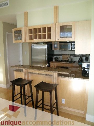 Modern kitchen with wooden cabinets, granite countertops, and stainless steel appliances. - 3005 - 1483 Homer Street, Vancouver Downtown