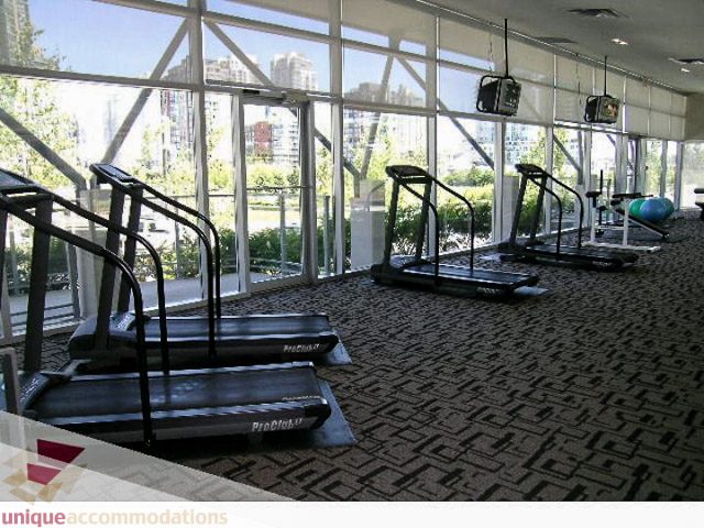 Bright gym with large windows, city view, and cardio equipment. - 2706 - 1438 Richards Street, Vancouver Downtown