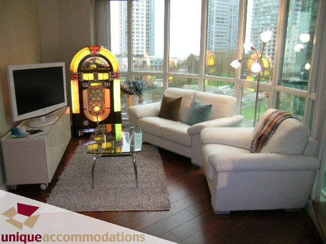 Spacious living room with hardwood floors, a retro jukebox, and a city view. - 306 - 588 Broughton Street, Vancouver Downtown