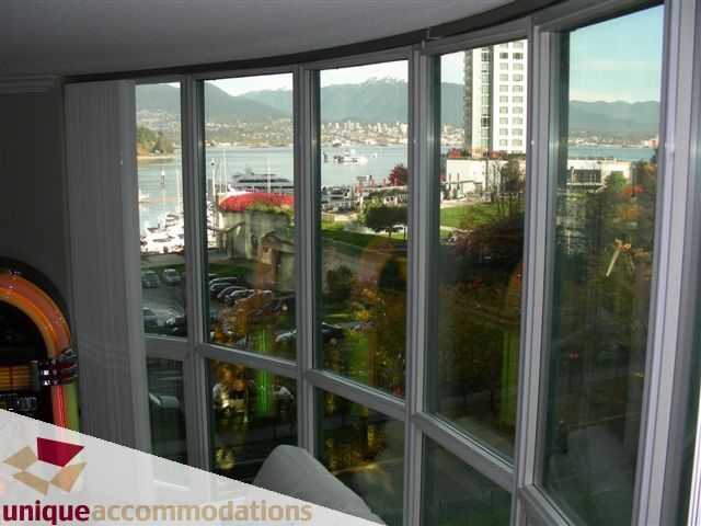 Spacious 1-bedroom + den condo with a stunning city view, featuring large windows and a cozy living area.