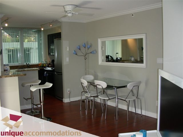 Modern kitchen with sleek countertops, hardwood floors, and a city view. - 306 - 588 Broughton Street, Vancouver Downtown