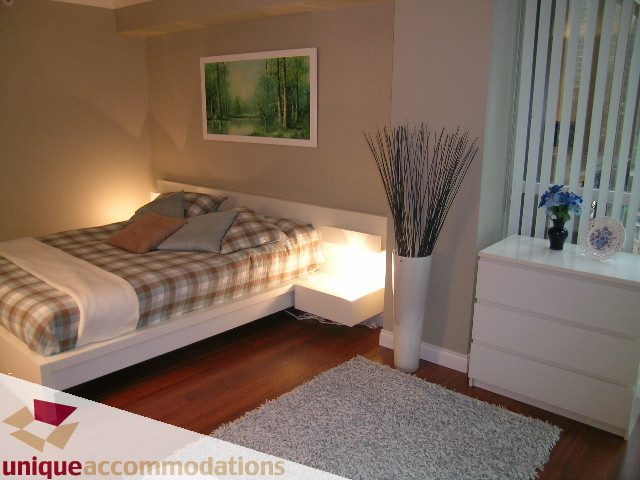 Spacious 1-bedroom + den condo with hardwood floors, cozy plaid bedding, and a modern shag rug. - 306 - 588 Broughton Street, Vancouver Downtown