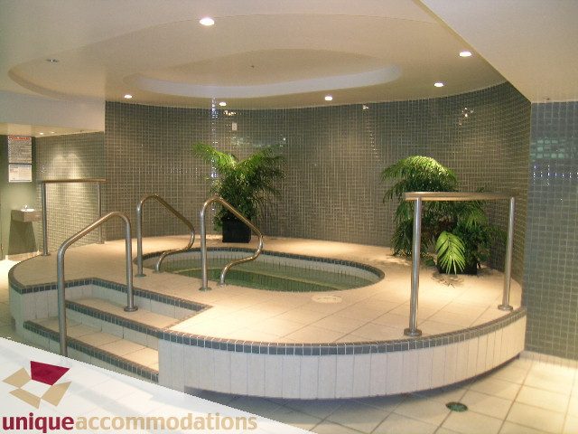 Spacious, modern 1-bedroom + den condo with a cozy corner spa featuring tiled walls, plants, and a relaxing ambiance.