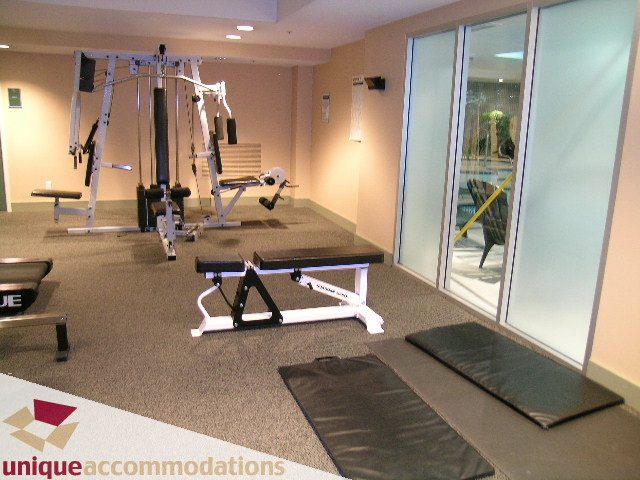 Furnished gym with cardio equipment, mats, and sliding glass doors to pool view. - 306 - 588 Broughton Street, Vancouver Downtown