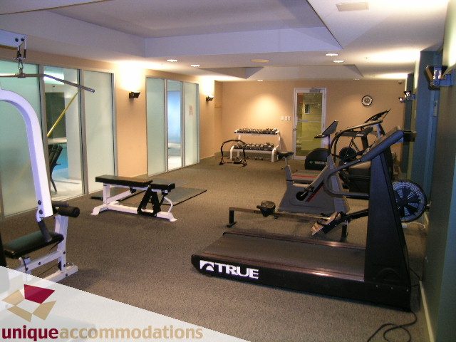 Furnished 1-bedroom + den condo with modern gym featuring treadmills, weight machines, and mirrors. - 306 - 588 Broughton Street, Vancouver Downtown