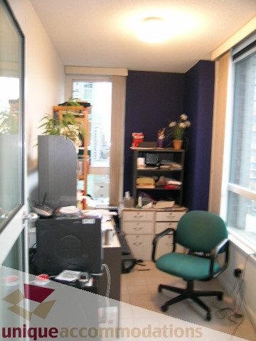 Spacious living room with a city view, modern furniture, and a comfortable chair. - 1306-388 Drake St, Vancouver Downtown