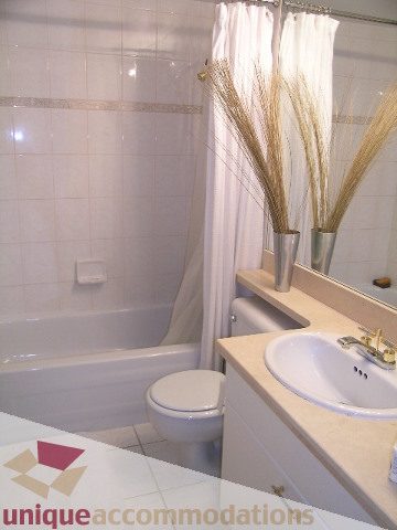 Furnished bathroom with white countertops, a bathtub, and decorative wheat stalks. - 1306-388 Drake St, Vancouver Downtown