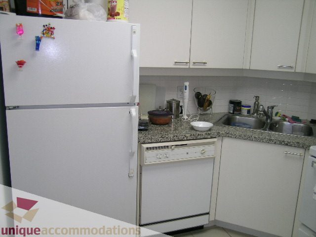 Bright kitchen with white cabinets, granite countertops, and a compact layout. - 1306-388 Drake St, Vancouver Downtown