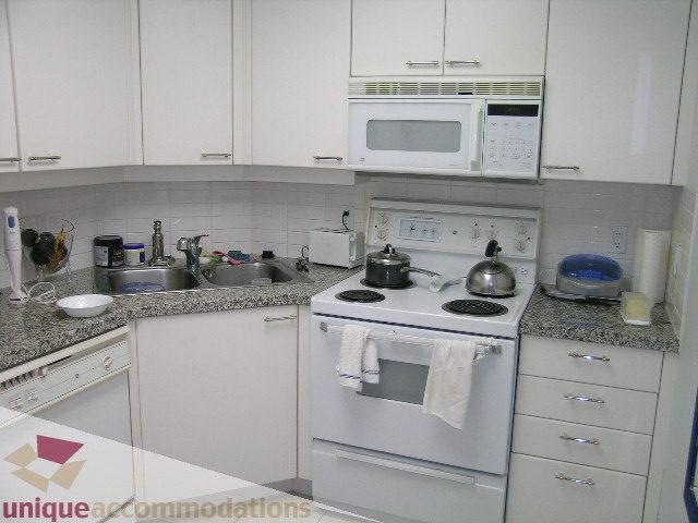 Bright kitchen with white cabinets, granite countertops, and a modern stove. - 1306-388 Drake St, Vancouver Downtown