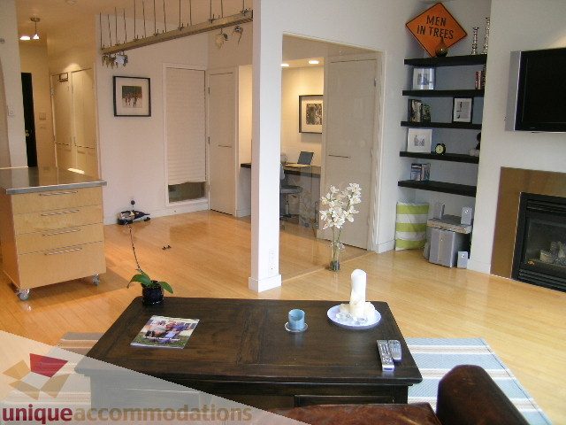 Furnished living room with hardwood floors, modern decor, and a cozy corner with a coffee table and magazines.