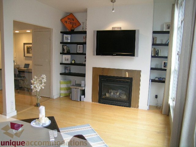 Living room with hardwood floors, modern decor, and a flat-screen TV mounted on the wall. - 503-1072 Hamilton St., Vancouver Downtown