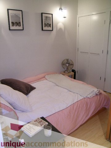 Furnished bedroom with hardwood floors and a cozy bed setup. - 503-1072 Hamilton St., Vancouver Downtown