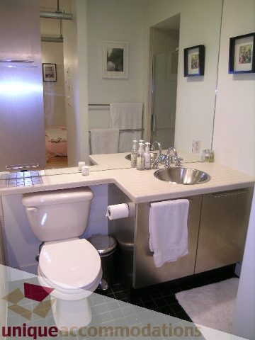 Bright bathroom with modern sink, large mirror, and white towels. - 503-1072 Hamilton St., Vancouver Downtown