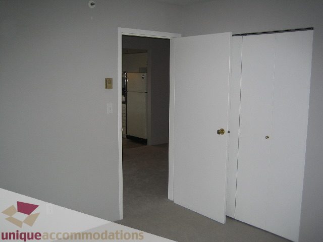 Bright bedroom with white closet doors and carpeted floor. - 1906 - 1060 Alberni Street, Vancouver Downtown