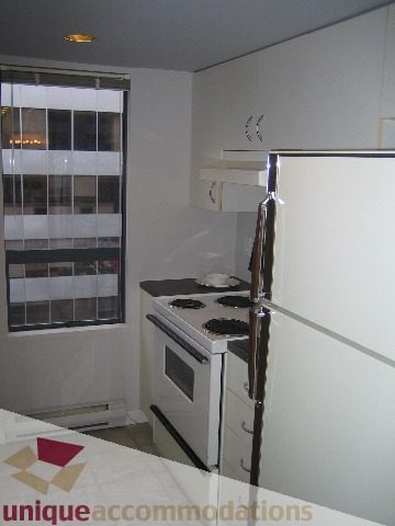 Bright kitchen with white cabinets, stainless steel appliances, and a city view. - 1906 - 1060 Alberni Street, Vancouver Downtown