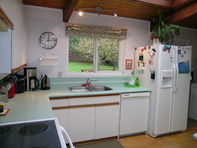 Bright kitchen with light green countertops, white cabinets, and a view of the backyard. - 433 Fairway Drive, North Vancouver