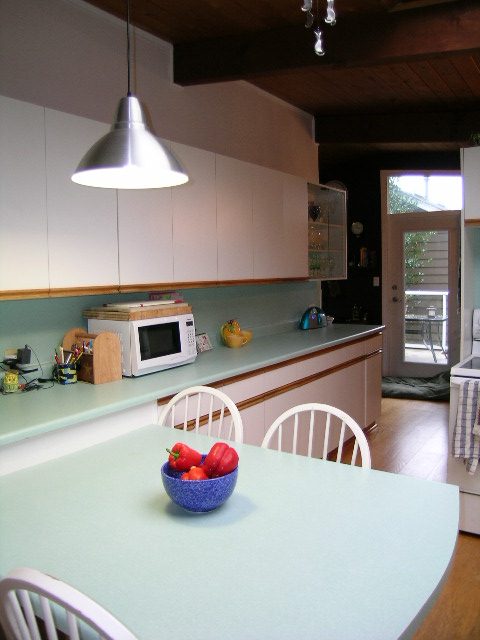 Bright kitchen with mint green countertops and white cabinets, featuring a bowl of red peppers on the island. - 433 Fairway Drive, North Vancouver