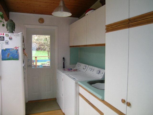Bright kitchen with white cabinets, teal countertops, and hardwood floors. - 433 Fairway Drive, North Vancouver