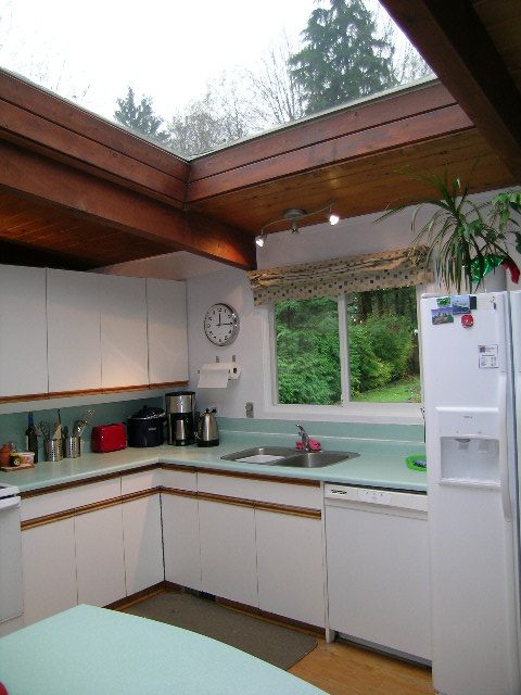 Bright kitchen with mint green countertops, hardwood floors, and a skylight view of trees. - 433 Fairway Drive, North Vancouver