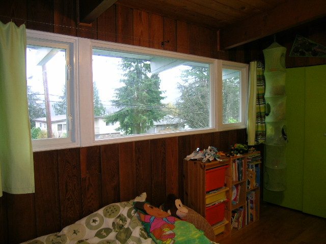 Bright bedroom with wooden walls, large windows, and colorful storage shelves. - 433 Fairway Drive, North Vancouver