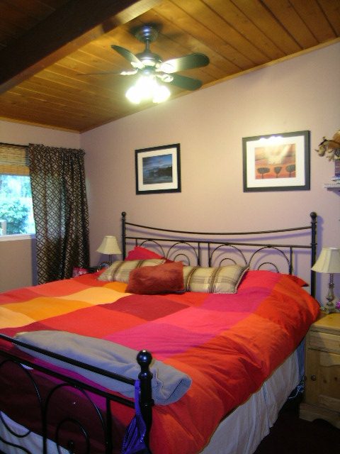 Spacious bedroom with colorful bedding, wooden ceiling fan, and framed artwork. - 433 Fairway Drive, North Vancouver