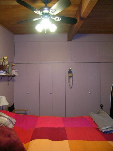 Bedroom with colorful bedding, wooden ceiling fan, and closet doors. - 433 Fairway Drive, North Vancouver
