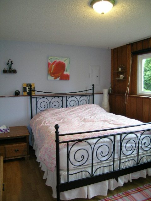 Bright bedroom with twin beds, wooden headboard, and a window view. - 433 Fairway Drive, North Vancouver