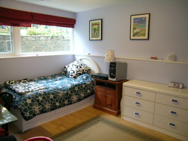 Bright bedroom with wooden floors, white dresser, and floral bedding. - 433 Fairway Drive, North Vancouver
