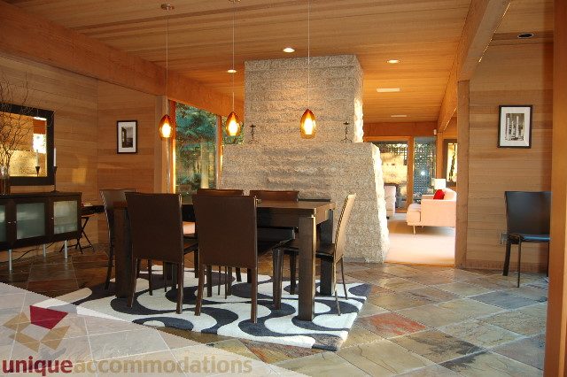 Furnished dining area with wooden walls, stone fireplace, and modern lighting. - 6290 Collingwood Street, Vancouver West Side