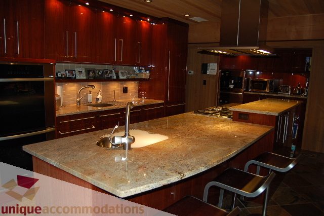 Bright kitchen with granite countertops, stainless steel appliances, and dark wood cabinets. - 6290 Collingwood Street, Vancouver West Side