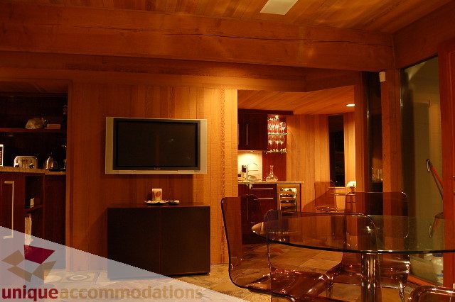 Furnished living room with wood-paneled walls and a modern TV setup. - 6290 Collingwood Street, Vancouver West Side