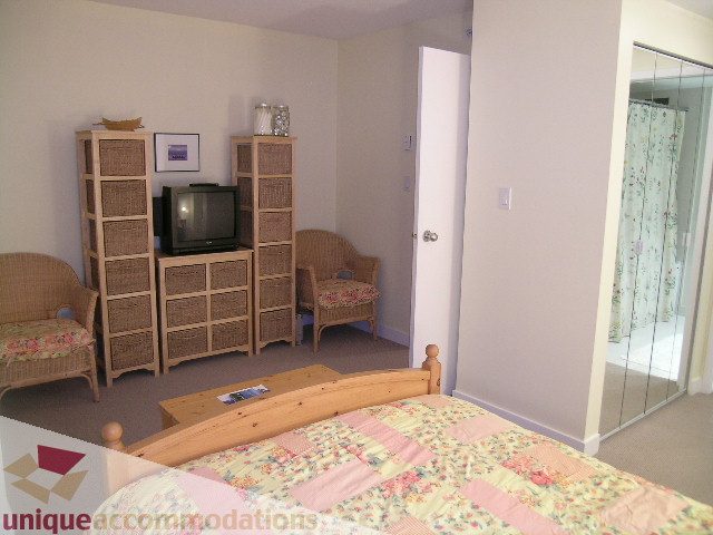 Bright bedroom with floral bedding and mirrored closet, wicker furniture, and wooden accents. - 1430 Strathmore Mews, Vancouver Downtown