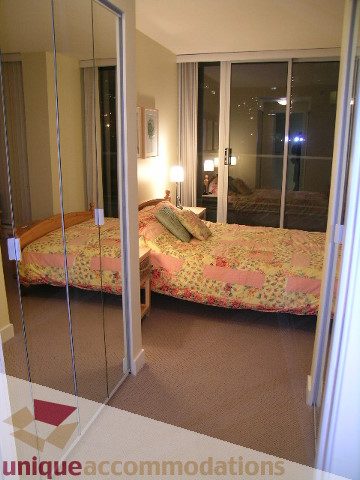 Spacious bedroom with mirrored closet doors and floral bedding. - 1430 Strathmore Mews, Vancouver Downtown