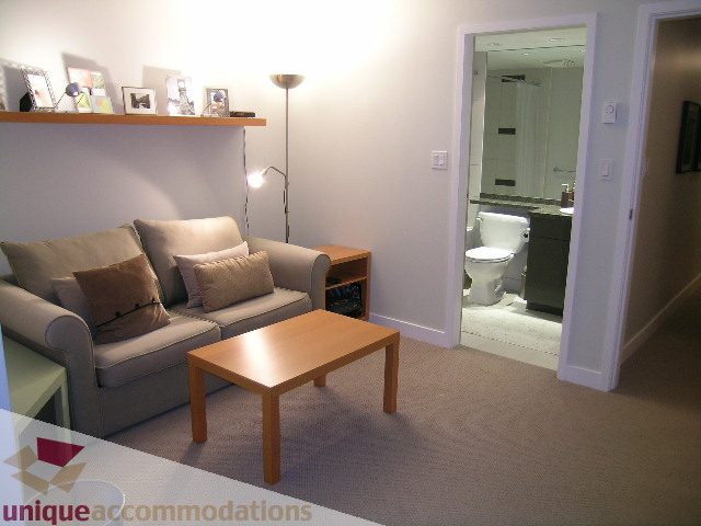 Furnished living room with a sofa, coffee table, and bathroom access. - 1430 Strathmore Mews, Vancouver Downtown