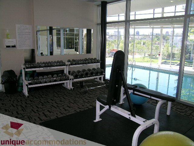 Fitness room with dumbbells, mirrors, and city view. - 1430 Strathmore Mews, Vancouver Downtown