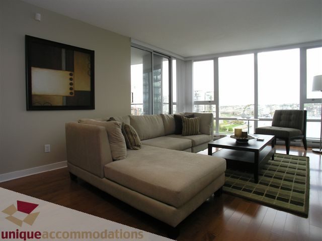 Spacious living room with large windows, hardwood floors, and a city view. - 1008 - 1408 Strathmore Mews, Vancouver Downtown