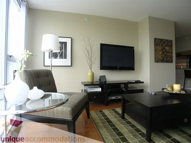 Spacious living room with modern decor, large windows, and a sleek coffee table. - 1008 - 1408 Strathmore Mews, Vancouver Downtown