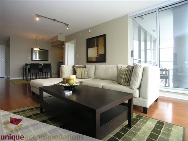 Spacious living room with hardwood floors, modern furniture, and a large sliding glass door leading to a balcony.