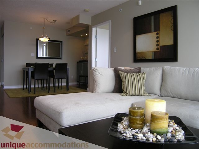Spacious living room with modern decor, featuring a cozy sofa, stylish artwork, and a sleek coffee table with candles.