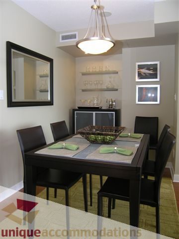 Furnished dining area with modern decor, dark wood chairs, and a sleek chandelier. - 1008 - 1408 Strathmore Mews, Vancouver Downtown