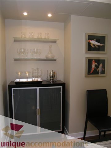 Spacious dining area with modern decor, wine glasses, and framed art, perfect for entertaining. - 1008 - 1408 Strathmore Mews, Vancouver Downtown