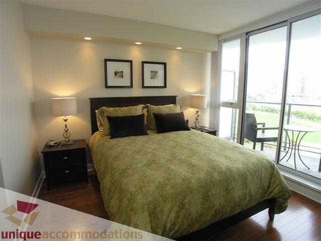 Spacious bedroom with hardwood floors, green bedding, and a city view from the large window. - 1008 - 1408 Strathmore Mews, Vancouver Downtown