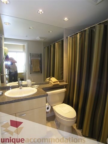 Spacious bathroom with granite countertops and a modern shower curtain. - 1008 - 1408 Strathmore Mews, Vancouver Downtown