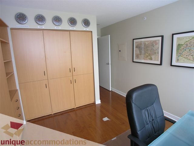 Spacious bedroom with wooden closet, hardwood floors, and framed maps on the wall. - 1008 - 1408 Strathmore Mews, Vancouver Downtown