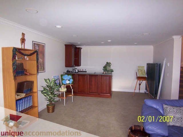 Spacious living room with hardwood floors, a blue couch, and a bookshelf. - 1659 Langton Place, West Vancouver