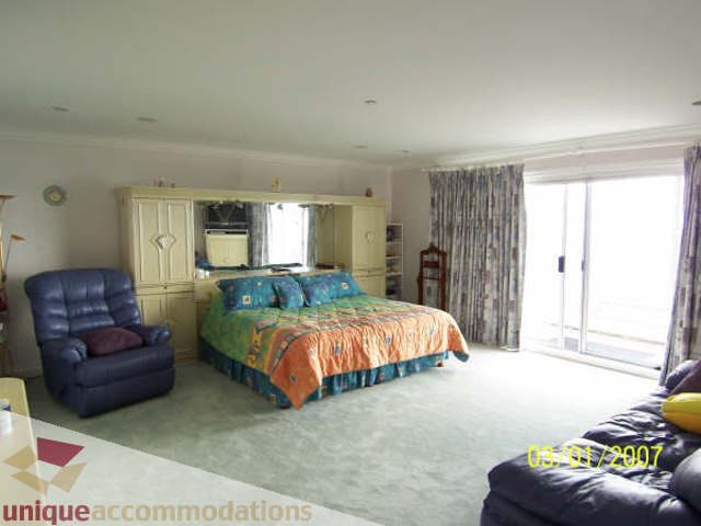 Spacious living room with large windows, colorful bedding, and a comfortable recliner. - 1659 Langton Place, West Vancouver